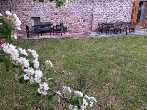 a group of tables and chairs in a yard with white flowers at gîte des marguerites in Montigny-en-Morvan