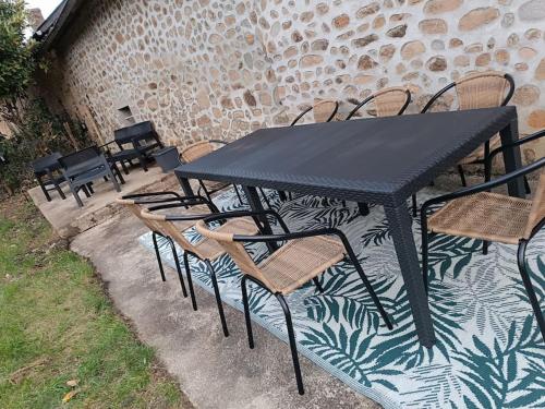 a black table and chairs sitting next to a brick wall at gîte des marguerites in Montigny-en-Morvan