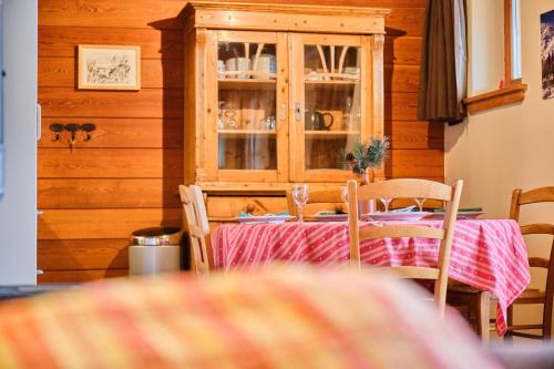 a dining room with a table with chairs and a cabinet at Chalet il fera beau demain in Villard-Reculas
