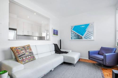 a living room with a white couch and a blue chair at Bondi Getaway - Parking and Walk to the Beach in Sydney