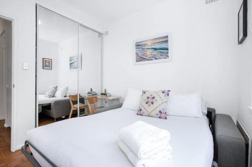 a bedroom with a white bed and a desk at Bondi Getaway - Parking and Walk to the Beach in Sydney