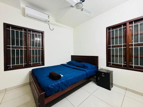 a bedroom with a blue bed and two windows at AL-Kabeer City Link suites in Trivandrum