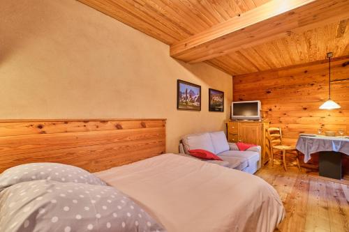 a bedroom with a bed and a table and a tv at Chalet il fera beau demain in Villard-Reculas