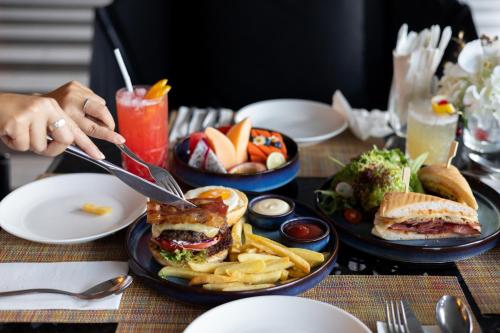 a table with plates of food with a sandwich and french fries at DoubleTree by Hilton Sukhumvit Bangkok in Bangkok