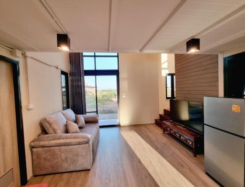 a living room with a couch and a refrigerator at Lan Nam Ob Duen ลานน้ำโอบเดือน in Si Khio