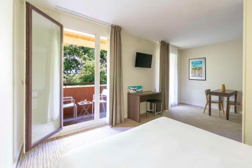 a hotel room with a bed and a sliding glass door at Kyriad Chambéry Centre - Hôtel et Résidence in Chambéry