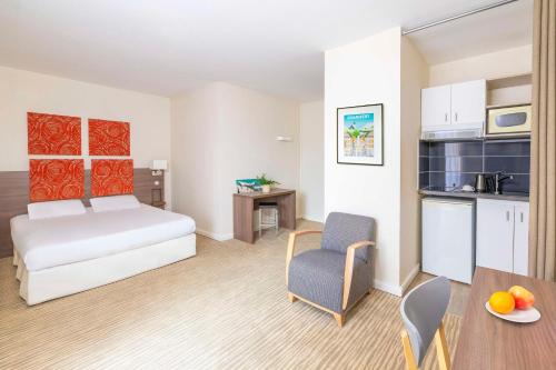 a room with a bed and a table and a kitchen at Kyriad Chambéry Centre - Hôtel et Résidence in Chambéry