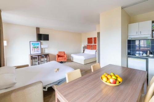 a living room with a table and a bedroom at Kyriad Chambéry Centre - Hôtel et Résidence in Chambéry