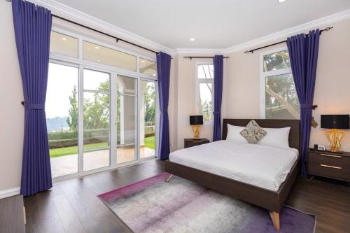 a bedroom with a bed with purple curtains and windows at Villa Khởi Nghĩa Bắc Sơn - Gần Chợ Đêm Gần Hồ XH Đà Lạt in Xuan An