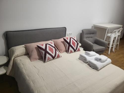 a bedroom with a bed with towels and a chair at Moderno y lujoso Apartamento CASTELAR 2 in Alcazar de San Juan