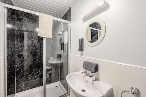 a white bathroom with a sink and a shower at Auchenlarie Courtyard No 2 in Gatehouse of Fleet