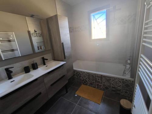 une salle de bain avec une baignoire, un lavabo et un miroir dans l'établissement villa récente climatisée avec piscine privée, à Vaison-la-Romaine