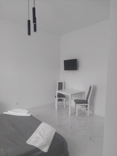 a white room with a table and chairs and a television at Apartamenty Nogalin in Józefów