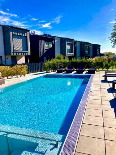 a swimming pool with lounge chairs next to a building at Apartments C'EST LA SEA - Whirlpool-Suite oder Dachterrassen-Suite in Neusiedl am See
