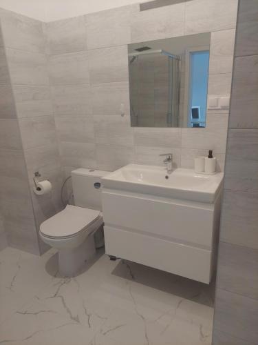 a white bathroom with a toilet and a sink at Apartamenty Nogalin in Józefów