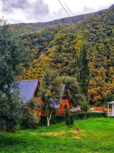 a red house in front of a hill with trees at Panorama cottages in Sno in Sno