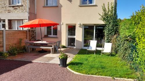 d'une terrasse avec une table et un parasol rouge. dans l'établissement Le logis du port, à Barneville-Carteret