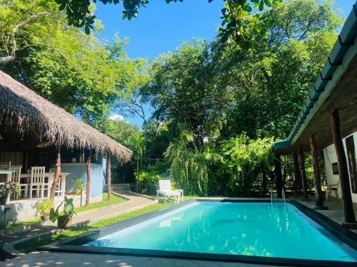 a swimming pool in front of a house with a building at Maritime Nest Cabanas in Tangalle