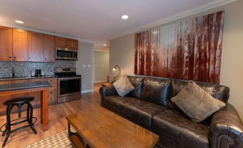 a living room with a leather couch and a kitchen at Prestige Hudson Bay Lodge & Conference Centre, WorldHotels Crafted Collection in Smithers