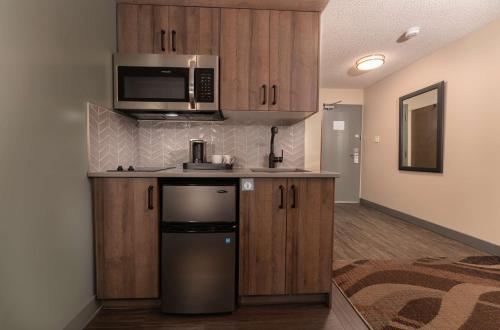 a kitchen with a refrigerator and a microwave at Prestige Hudson Bay Lodge & Conference Centre, WorldHotels Crafted Collection in Smithers