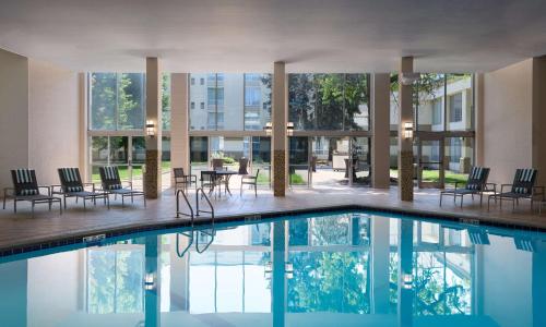 a pool in a building with chairs and tables at DoubleTree by Hilton Minneapolis Airport, MN in Bloomington