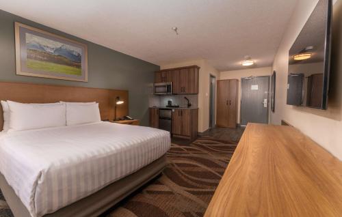 a hotel room with a bed and a kitchen at Prestige Hudson Bay Lodge & Conference Centre, WorldHotels Crafted Collection in Smithers