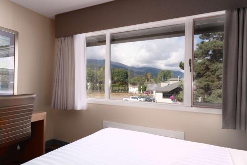 a bedroom with a bed and a window with a view at Prestige Hudson Bay Lodge & Conference Centre, WorldHotels Crafted Collection in Smithers