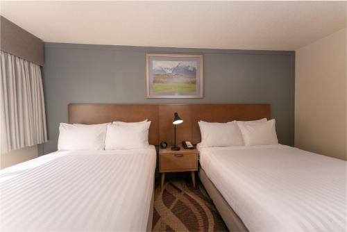 a hotel room with two beds and a night stand at Prestige Hudson Bay Lodge & Conference Centre, WorldHotels Crafted Collection in Smithers