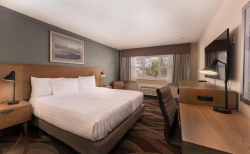 a hotel room with a bed and a desk and a window at Prestige Hudson Bay Lodge & Conference Centre, WorldHotels Crafted Collection in Smithers