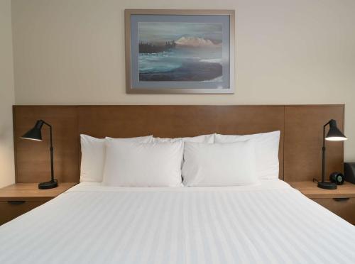 a bedroom with a large white bed with two lamps at Prestige Hudson Bay Lodge & Conference Centre, WorldHotels Crafted Collection in Smithers