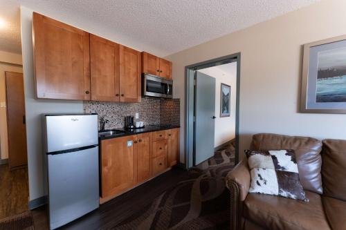 a kitchen with a refrigerator and a couch in a room at Prestige Hudson Bay Lodge & Conference Centre, WorldHotels Crafted Collection in Smithers