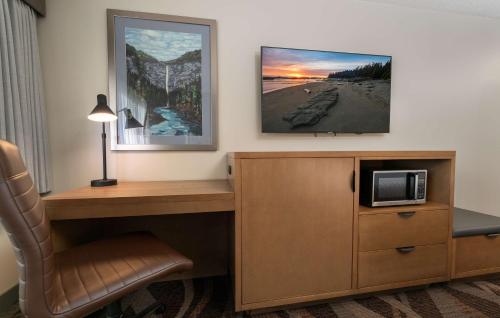 a room with a desk with a microwave and a chair at Prestige Hudson Bay Lodge & Conference Centre, WorldHotels Crafted Collection in Smithers