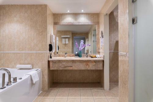 a bathroom with a tub and a large mirror at Warwick Al Jubail Hotel in Al Jubail