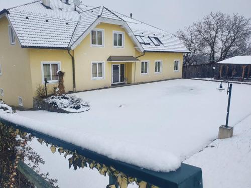 a house with a driveway covered in snow at Pension Familie Dunkl in Dietmannsdorf