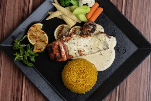 a plate of food with meat and rice and vegetables at Warwick Al Jubail Hotel in Al Jubail