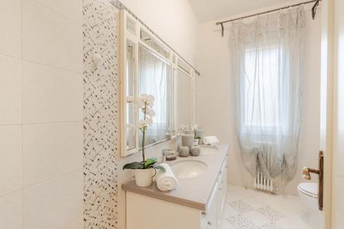 Un baño blanco con lavabo y espejo. en Martino 17, en Vicopisano