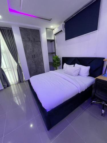 a bedroom with a large bed with white sheets at Wine House, Maitama, Abuja in Abuja