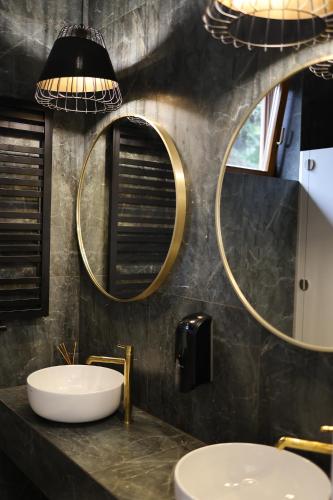 a bathroom with two sinks and two mirrors at Hotel i Restauracja Borowianka in Ostrów Wielkopolski