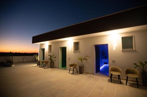 a patio with chairs and a blue door at night at Suite La PerlaNera- TorreCanne in Torre Canne