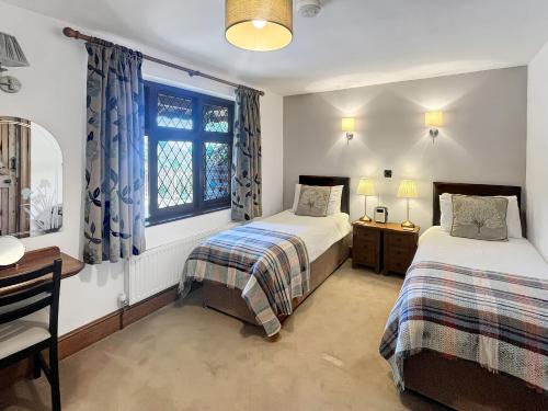 a bedroom with two beds and a desk and a window at Gardener’s Cottage Martinhoe in Martinhoe
