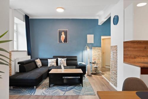 a living room with a black couch and a blue wall at BackHome - SUITE XL - Parkhaus - Fantastische Schlosslage - SmartTV - Waschmaschine - Netflix - 90qm - 24h Checkin- Apartment 6 in Ludwigsburg