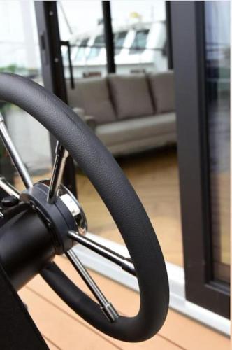 a steering wheel sitting in a room with a couch at Moderne houseboat op het water! in Assendelft