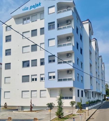 a tall white building with a sign on it at Apartman Jelena II in Banja Koviljača