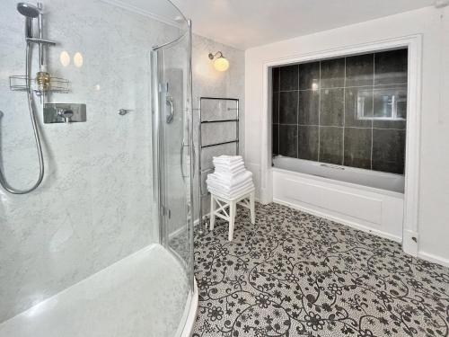 een badkamer met een douche en een bad en een raam bij Gamekeeper’s Cottage Martinhoe in Martinhoe