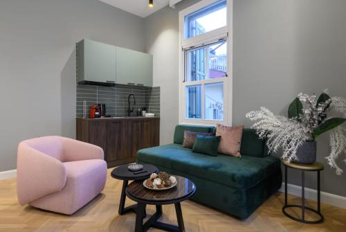 a living room with a green couch and a pink chair at The Zorbas Apartments in Mytilini