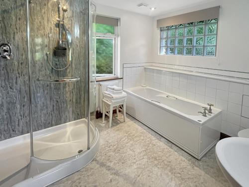 a bathroom with a tub and a shower and a sink at Chauffeur’s Cottage Martinhoe in Martinhoe