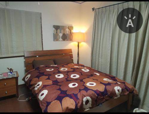 a bedroom with a bed with a flowery comforter at レンタルルーム目黒 in Tokyo