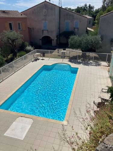 une grande piscine bleue dans une cour dans l'établissement Maison en Drôme provençale, à Nyons