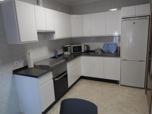 a kitchen with white cabinets and a white refrigerator at Casa Rural Fuente Vieja in Malpartida de Plasencia