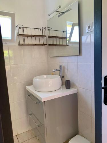 une salle de bain blanche avec un lavabo et un miroir dans l'établissement Le clos rozan, à Sainte-Eulalie-en-Born